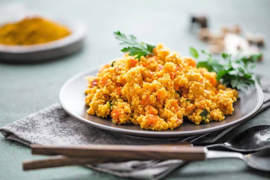 Couscous with garnishes on a grey plate