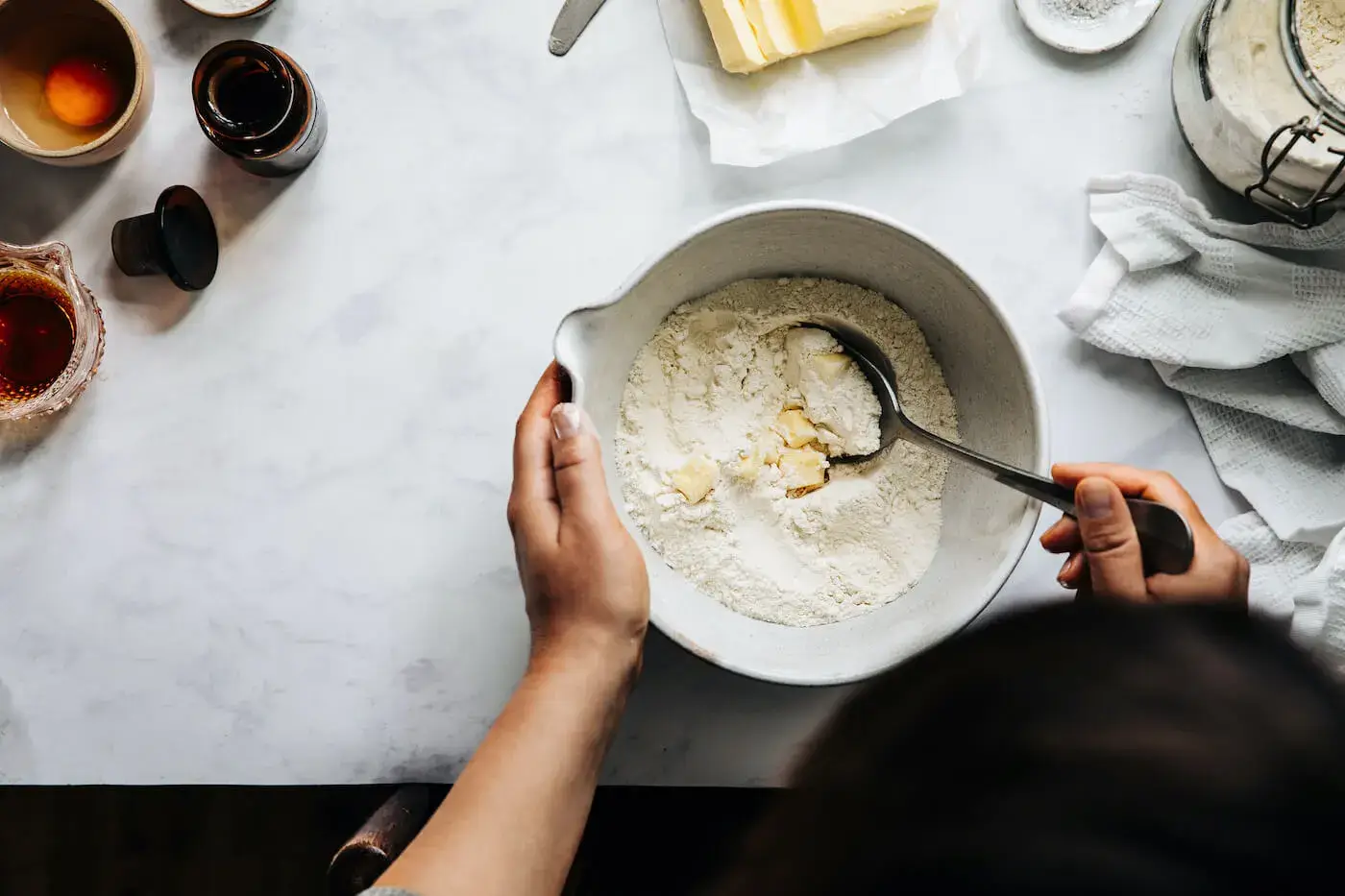 Hands mixing flour and butter in a ceramic bowl.