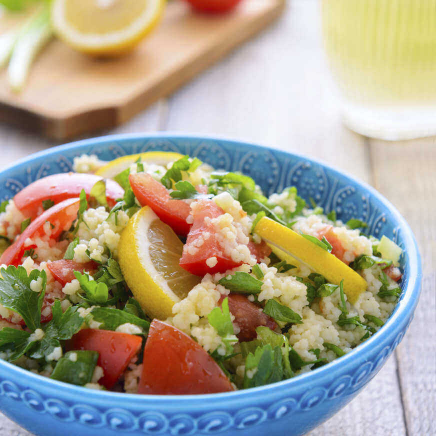 Salad with couscous, lemon, and tomatoes in a blue bowl