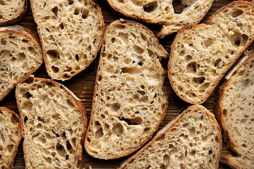 Slices of rustic sourdough bread with large air pockets and a crisp crust.