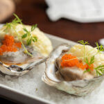 Oysters garnished with red caviar on salt and plate