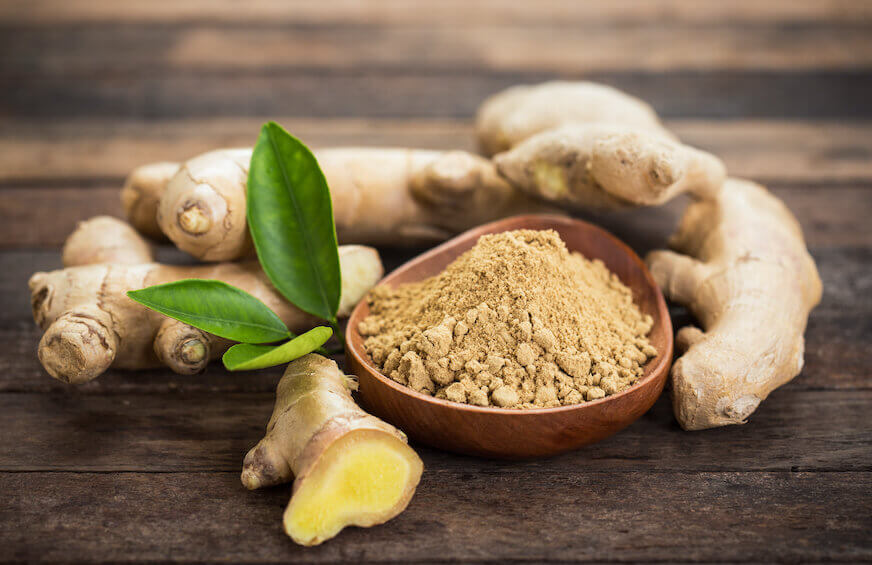 Ginger root next to a bowl of ginger powder