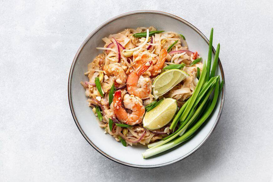 Pad Thai with shrimp, sprouts and green onions in a bowl