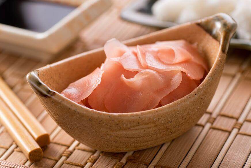 A wooden bowl with pink ginger