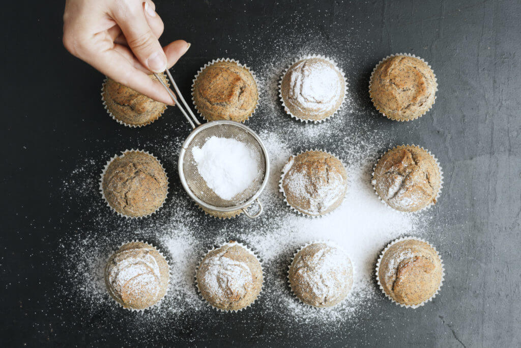 Sprinkling white powdered sugar over muffins