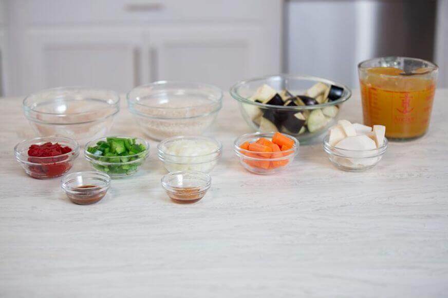 Broth, onions, carrots and other ingredients in glass bowls