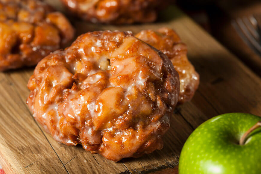 Glazed apple fritter next to a green apple
