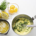 French mother sauce hollandaise in a metal pan with eggs and lemons on the side