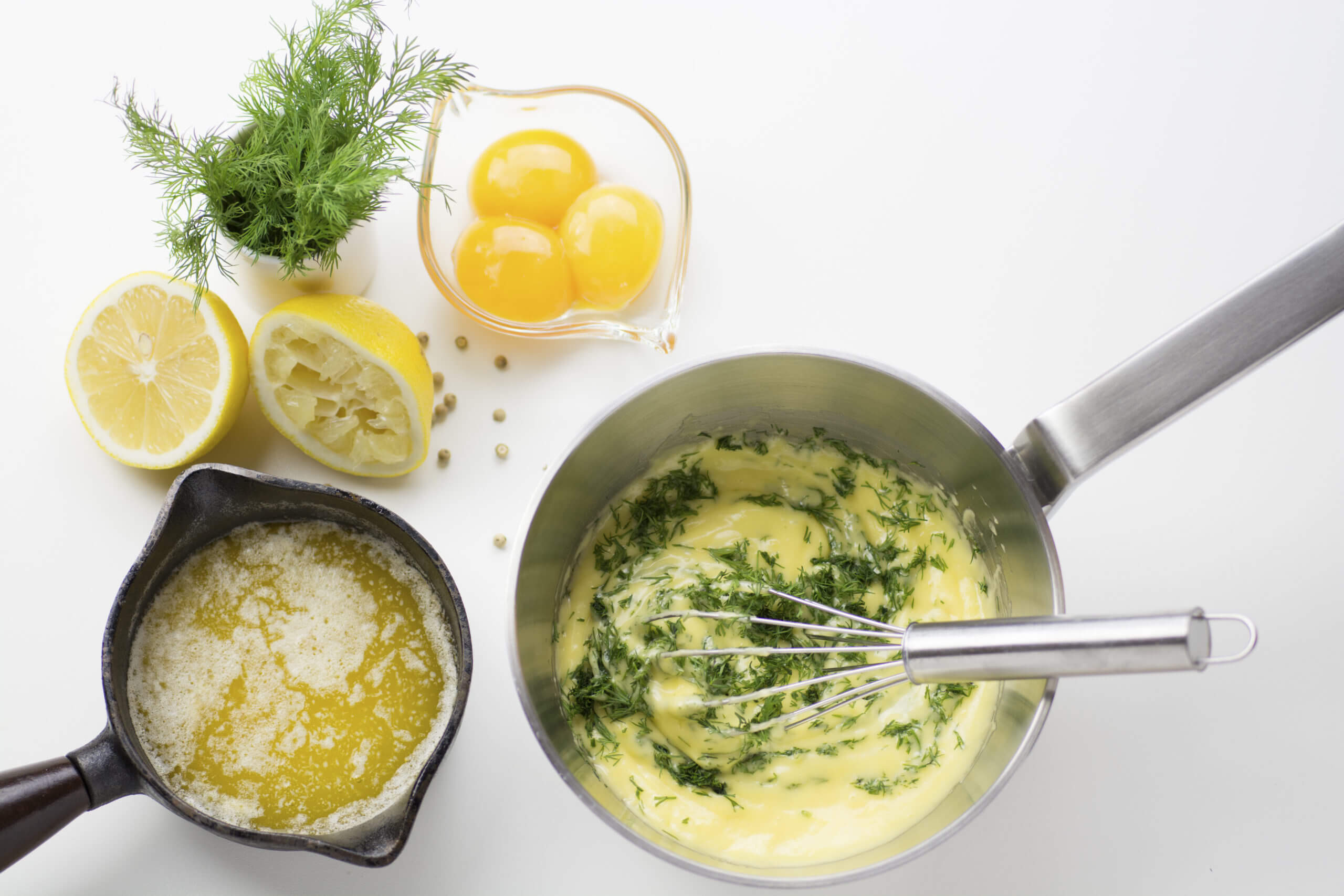 French mother sauce hollandaise in a metal pan with eggs and lemons on the side