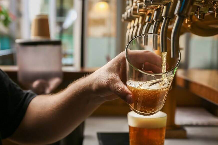 Bar employee pouring beer into a glass