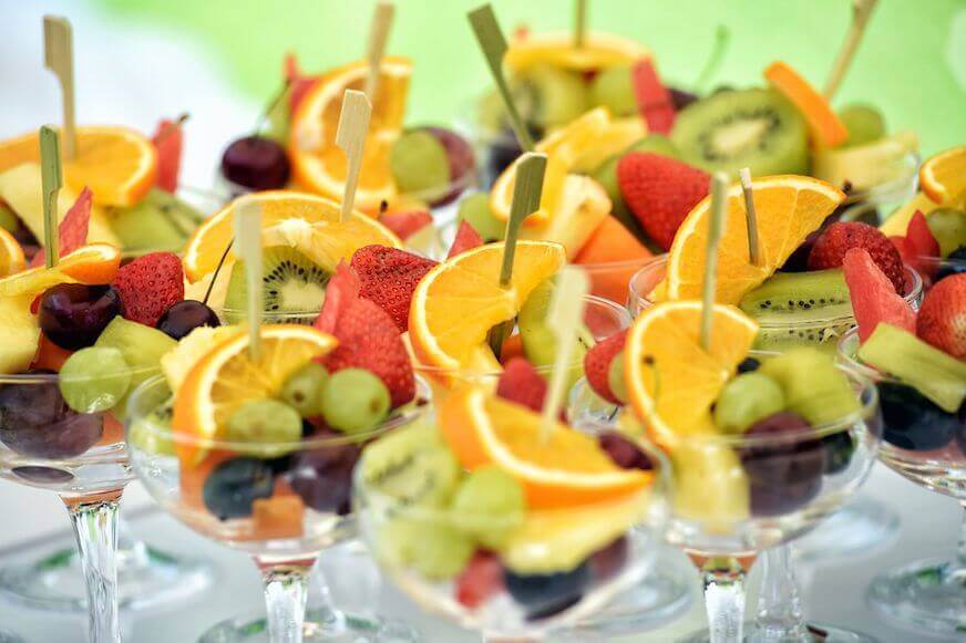 Assortment of fresh fruit cocktails in glasses on a buffet table.