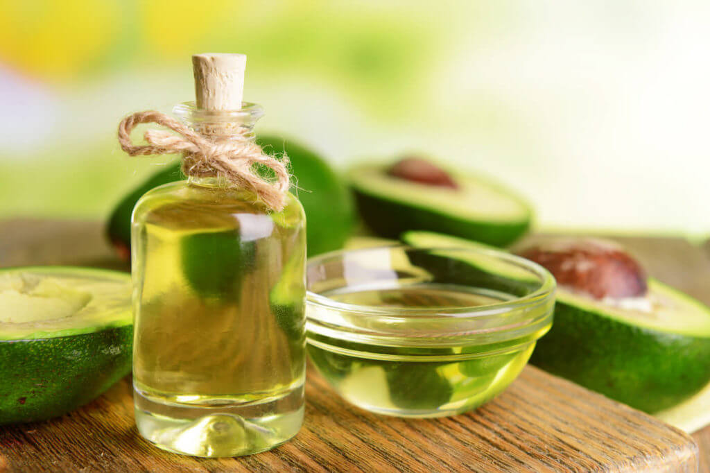 Avocado oil on table on light background