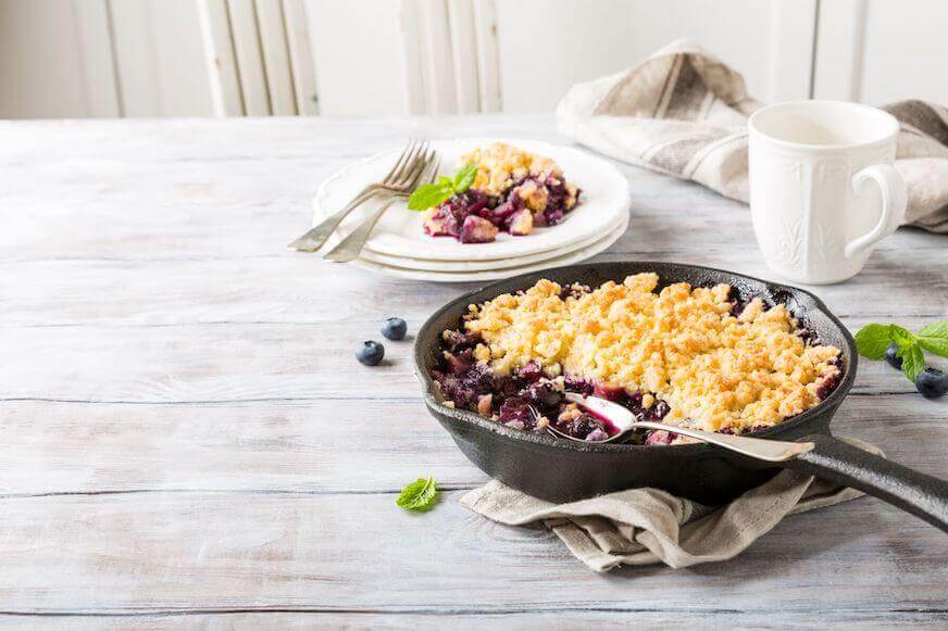 Coconut crumble in cast iron pan with fresh apples and blueberry