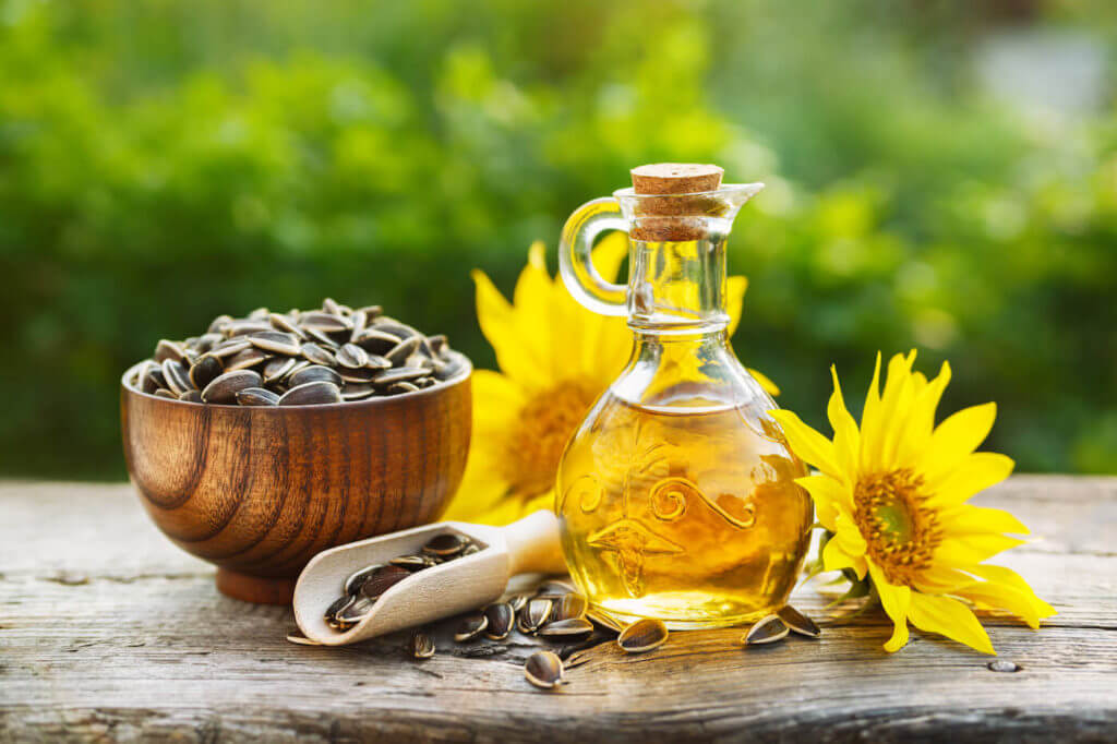 Organic sunflower oil in a small glass jar with sunflower seeds and fresh flowers