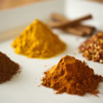 various yellow brown and red spices on a white board