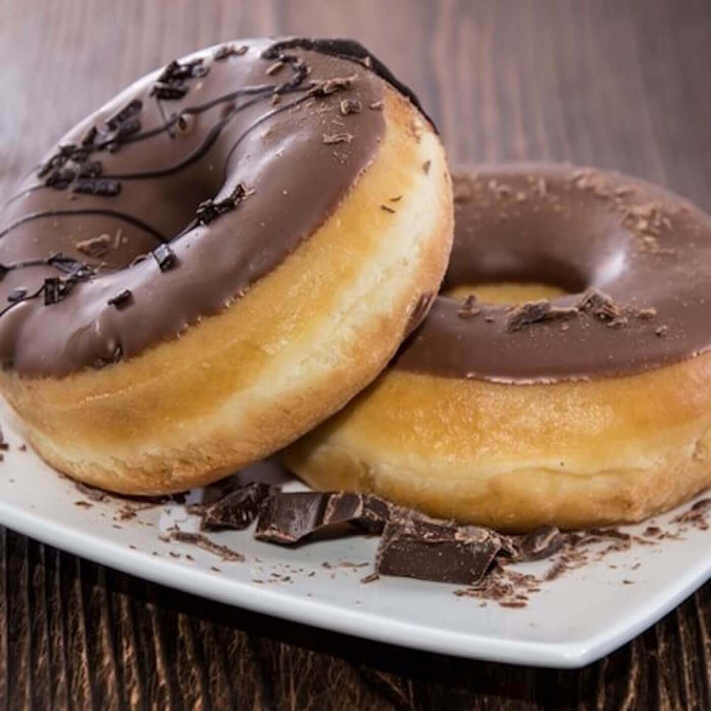 Two donuts with chocolate icing on a white plate