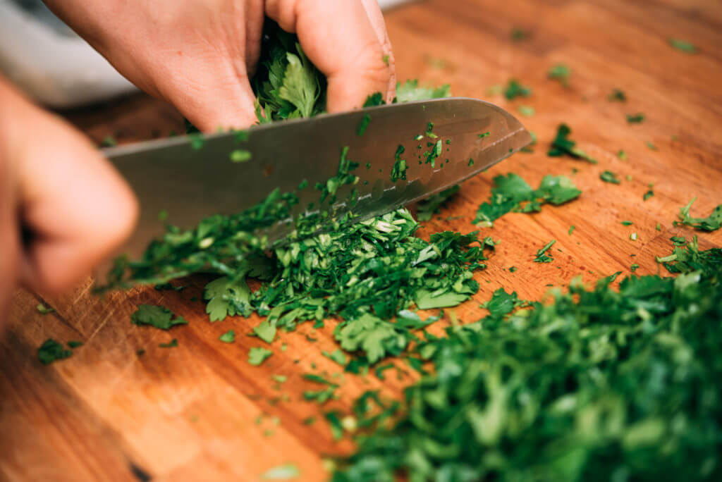 Chopping parsley cilantro on a wooden cutting board with knife