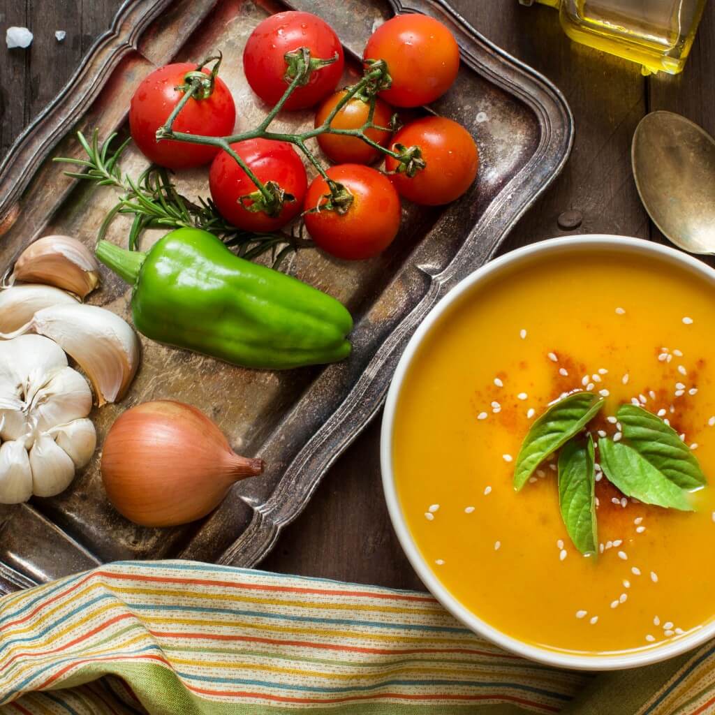 Fresh pumpkin soup and vegetables on a wooden table