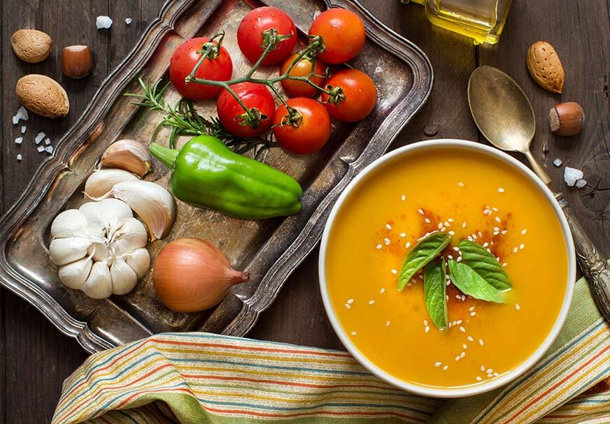 Fresh pumpkin soup and vegetables on a wooden table