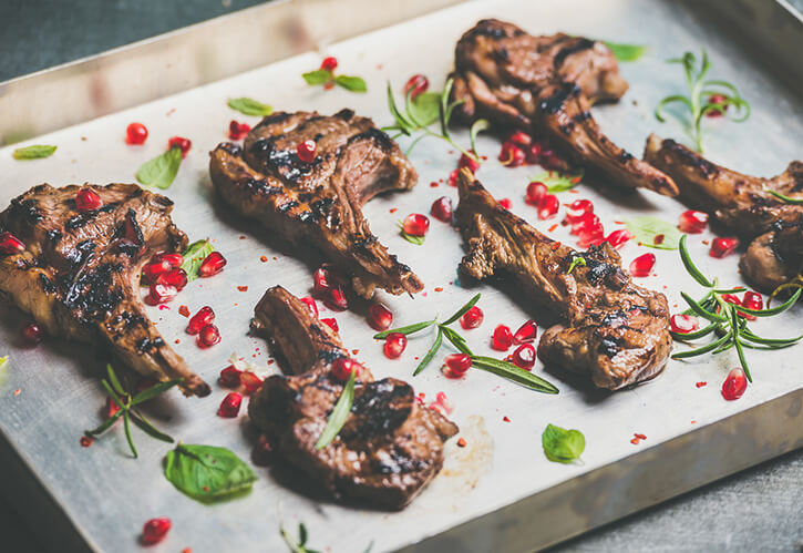 An array of lamp chops sprinkled with pomagranate seeds and herbs