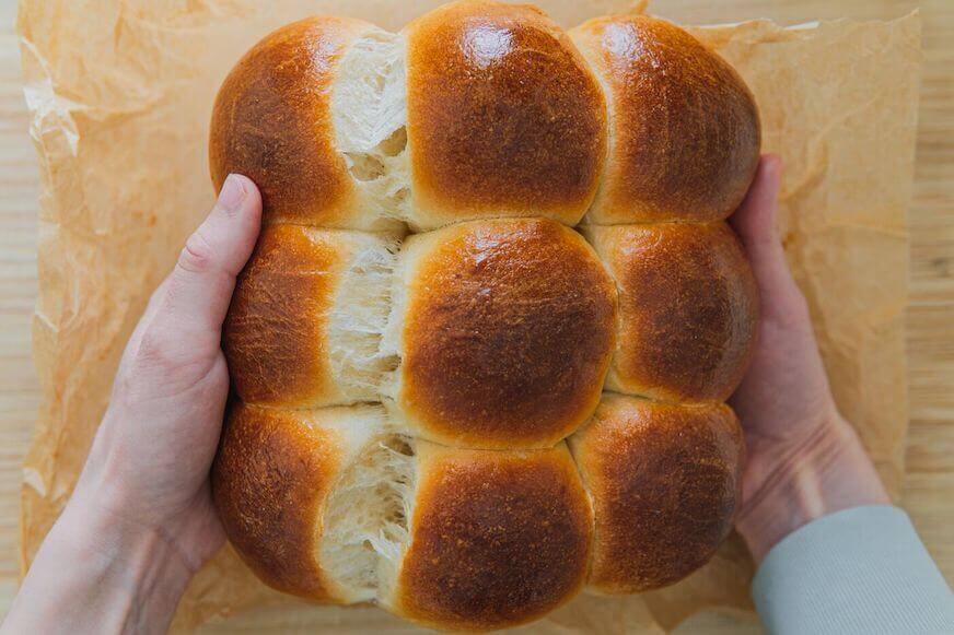 A pair of hands holds freshly-baked soft rolls.