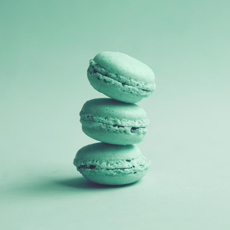 Three teal macarons stacked on top of each other.