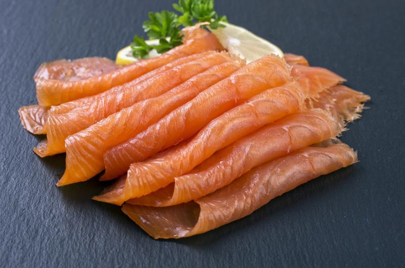 Smoked salmon pieces on black counter.