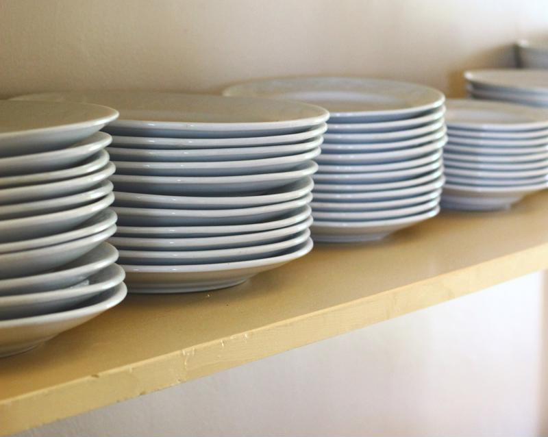 Open shelves filled with stacked white plates.