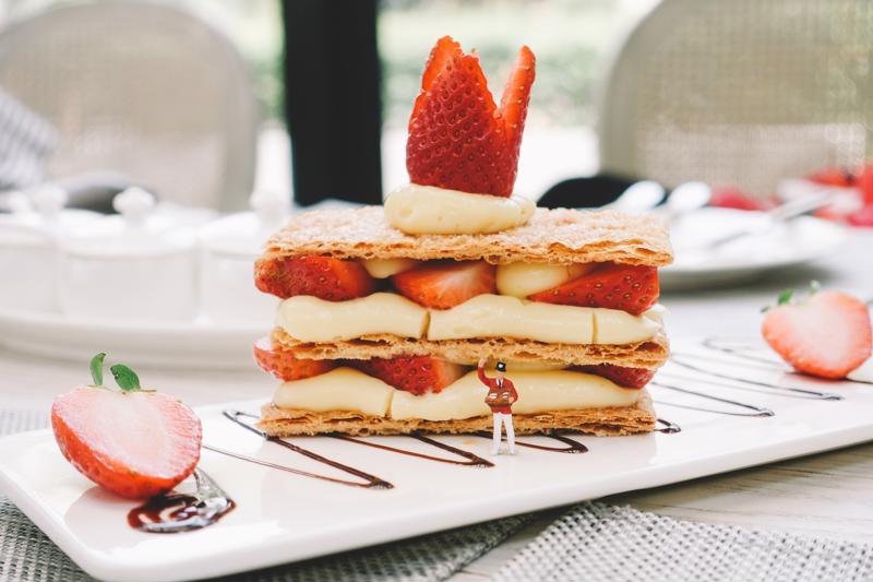Mille-feuille with strawberries and chocolate drizzle on white plate.