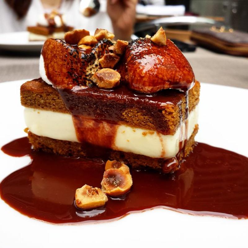 An ice cream sandwich topped with chocolate, hazelnuts and marshmallows sits on a white china plate.